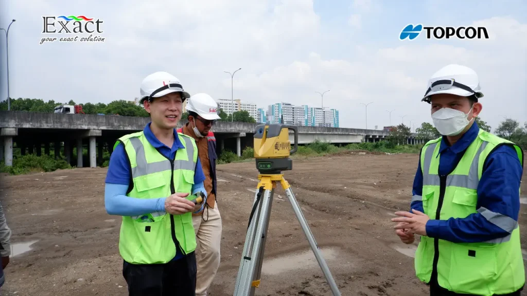 Operator sedang mengoperasikan alat Topcon ESN-100 dengan latar belakang struktur jembatan layang beton.